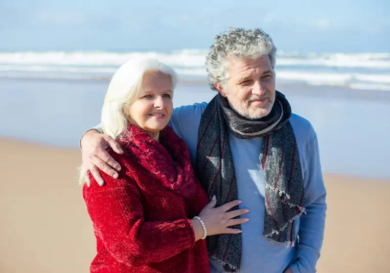 Older couple walking on the beach, symbolizing peace, support, and fulfillment in early retirement.